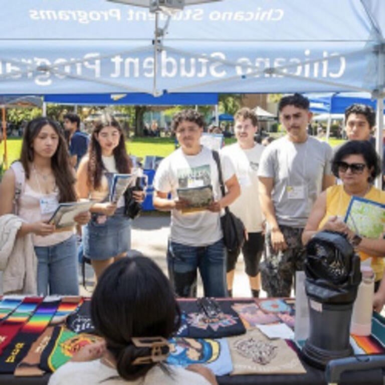 Students gathered around Chicano Student Programs table at orientation